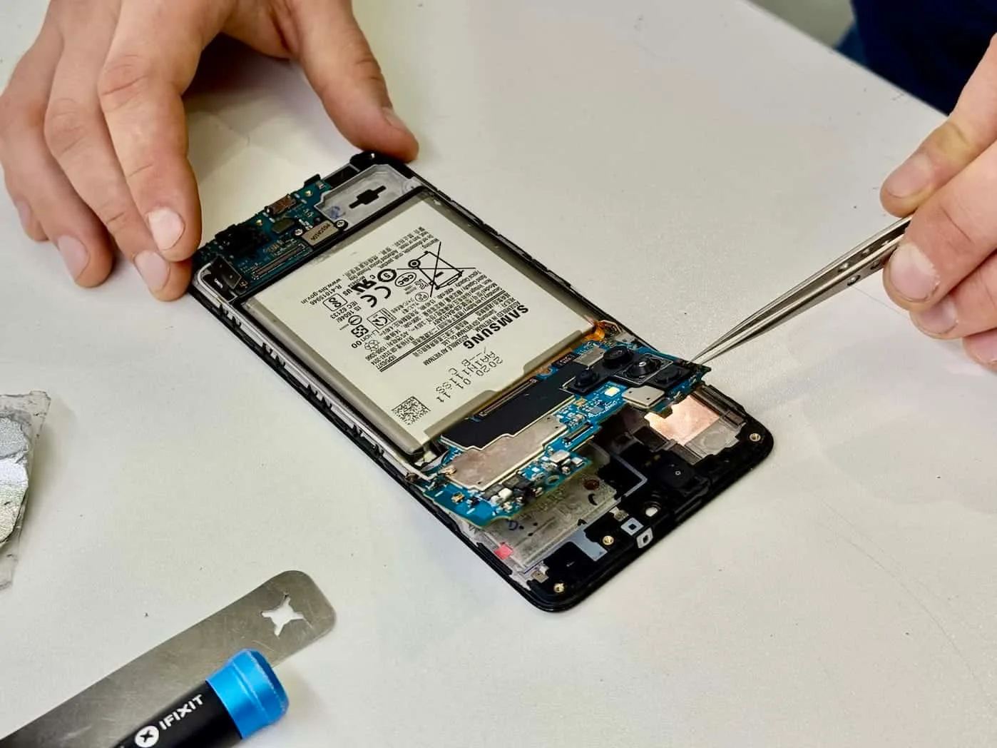 Samsung phone motherboard being removed on the bench