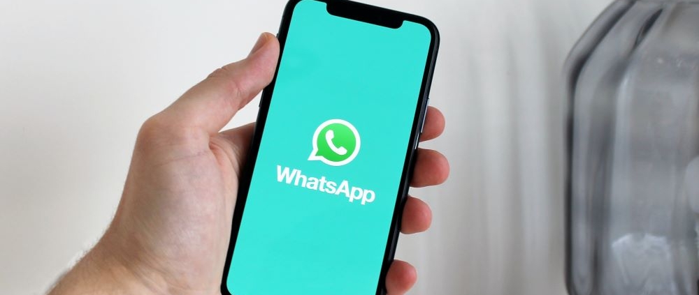 Hand holding iPhone with WhatsApp splash screen open for forensic extraction