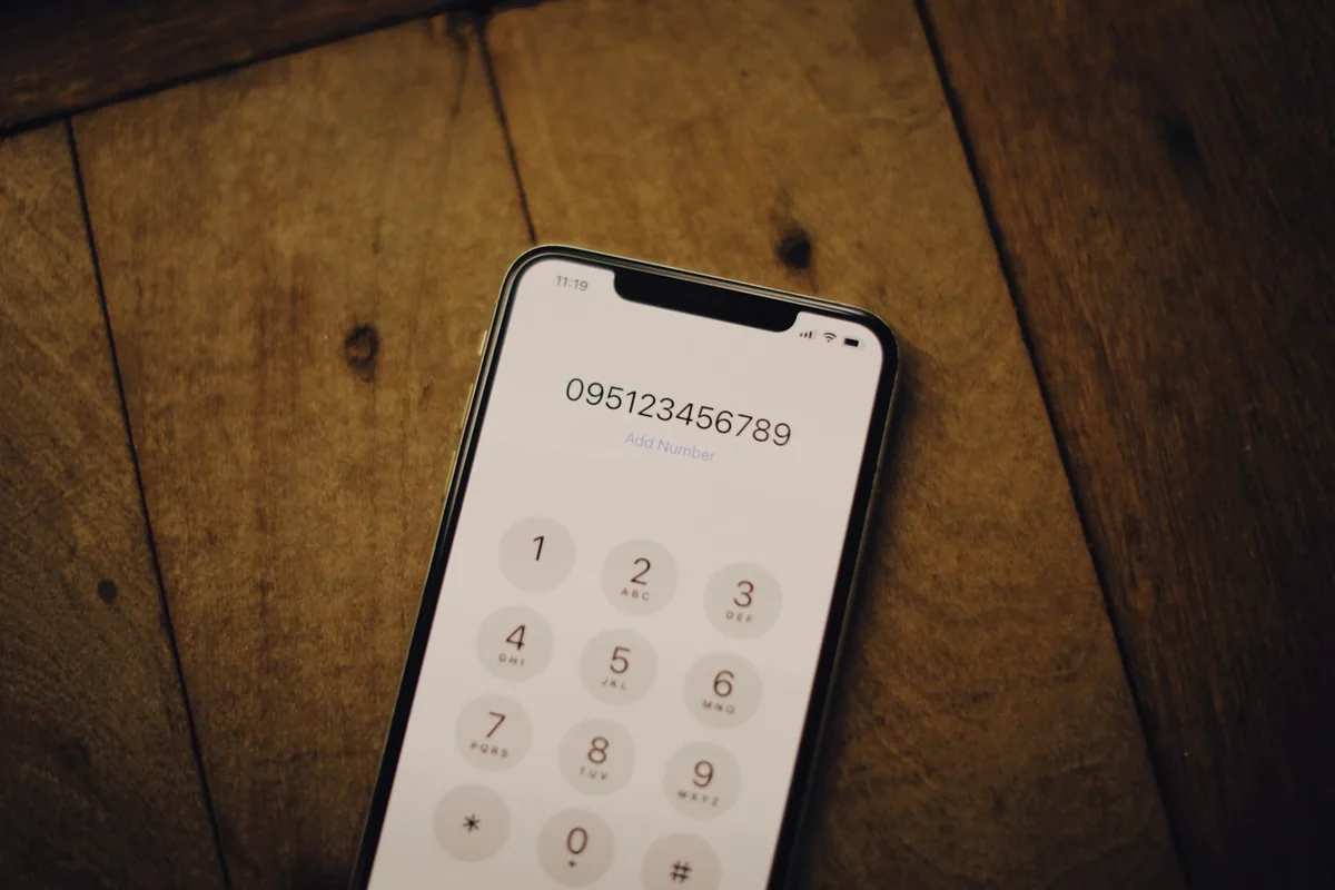 iPhone keypad on a wooden table, where the iPhone codes to check for spyware are dialled even though they only report call forwarding